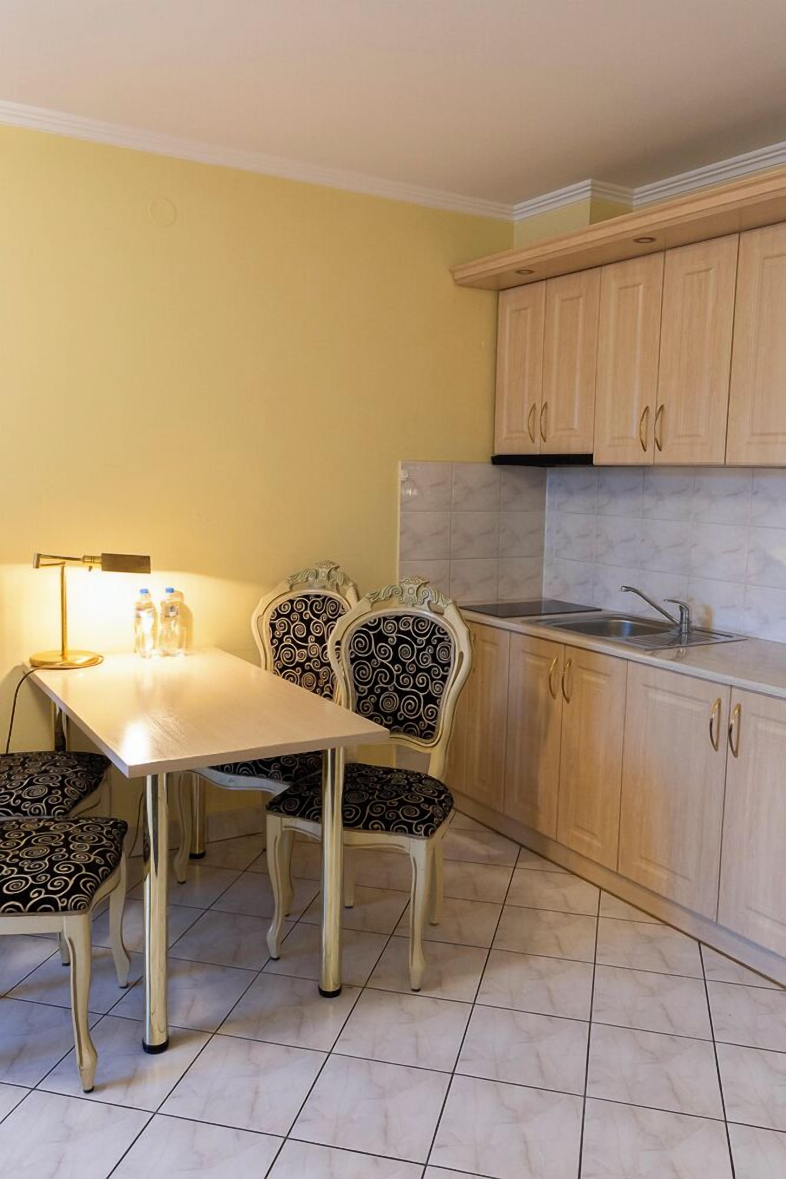 A compact kitchen with a dining table and chairs, a sink, and light wooden cabinets.