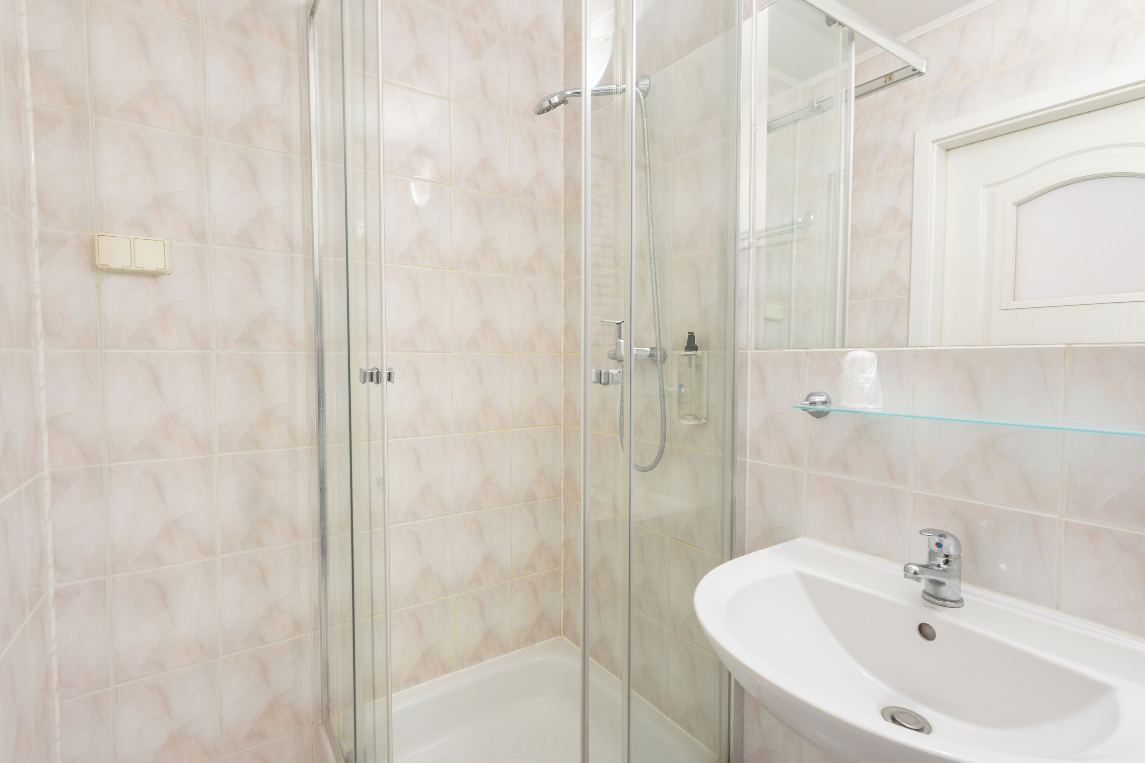 Un baño moderno con ducha de vidrio, un lavabo blanco y un espejo encima.