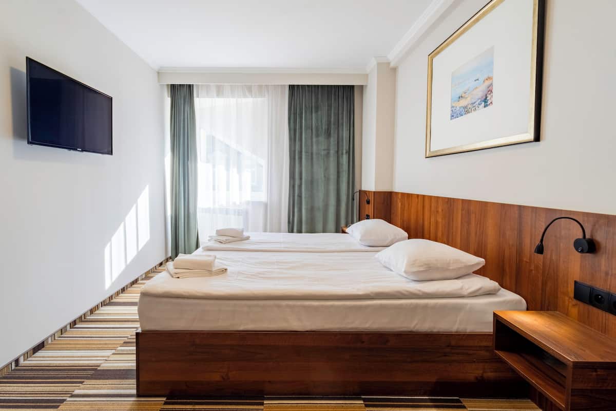 Een hotelkamer met een groot bed, een flatscreen televisie aan de muur, een houten hoofdbord en een inlijsting foto.