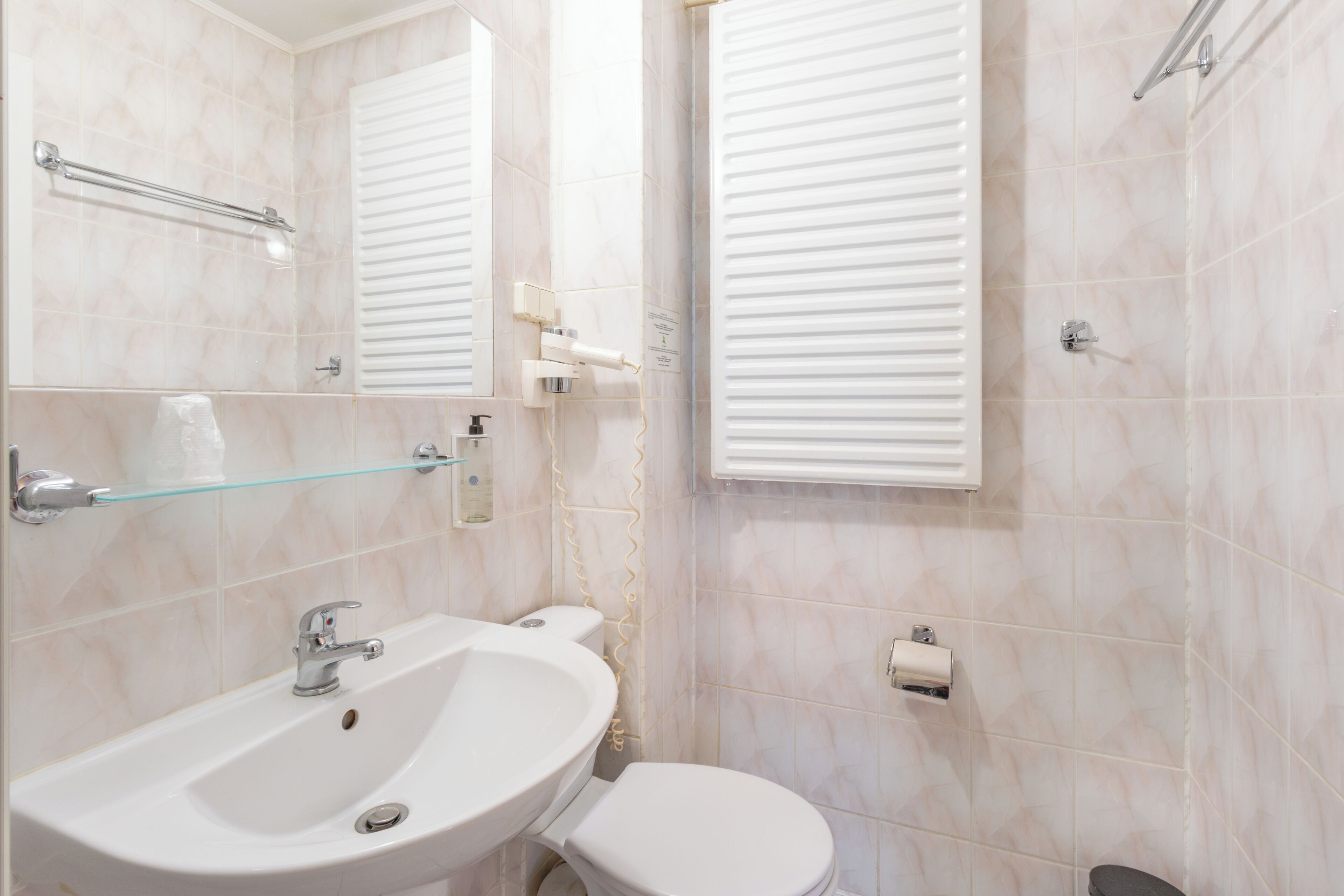Une salle de bain avec un lavabo blanc, des toilettes et une étagère en verre au-dessus du lavabo.