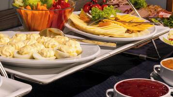 Uma mesa de buffet com diversos alimentos, incluindo legumes, queijo e carne.