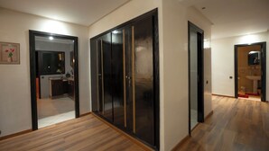 A hallway with a wooden floor, a black wardrobe with gold trim, and a mirror on the wall. - Luxury & Comfort apartment in the center, close to all amenities (Marrakesh)