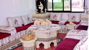 A spacious living room with a large window, a decorative chandelier, and a sofa set with intricate patterns. - Luxury & Comfort apartment in the center, close to all amenities (Marrakesh)