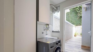 Ein modernes Badezimmer mit Waschmaschine, Waschbecken und Dusche.