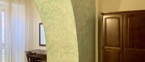 A bedroom with a bed, a desk, and a wardrobe.