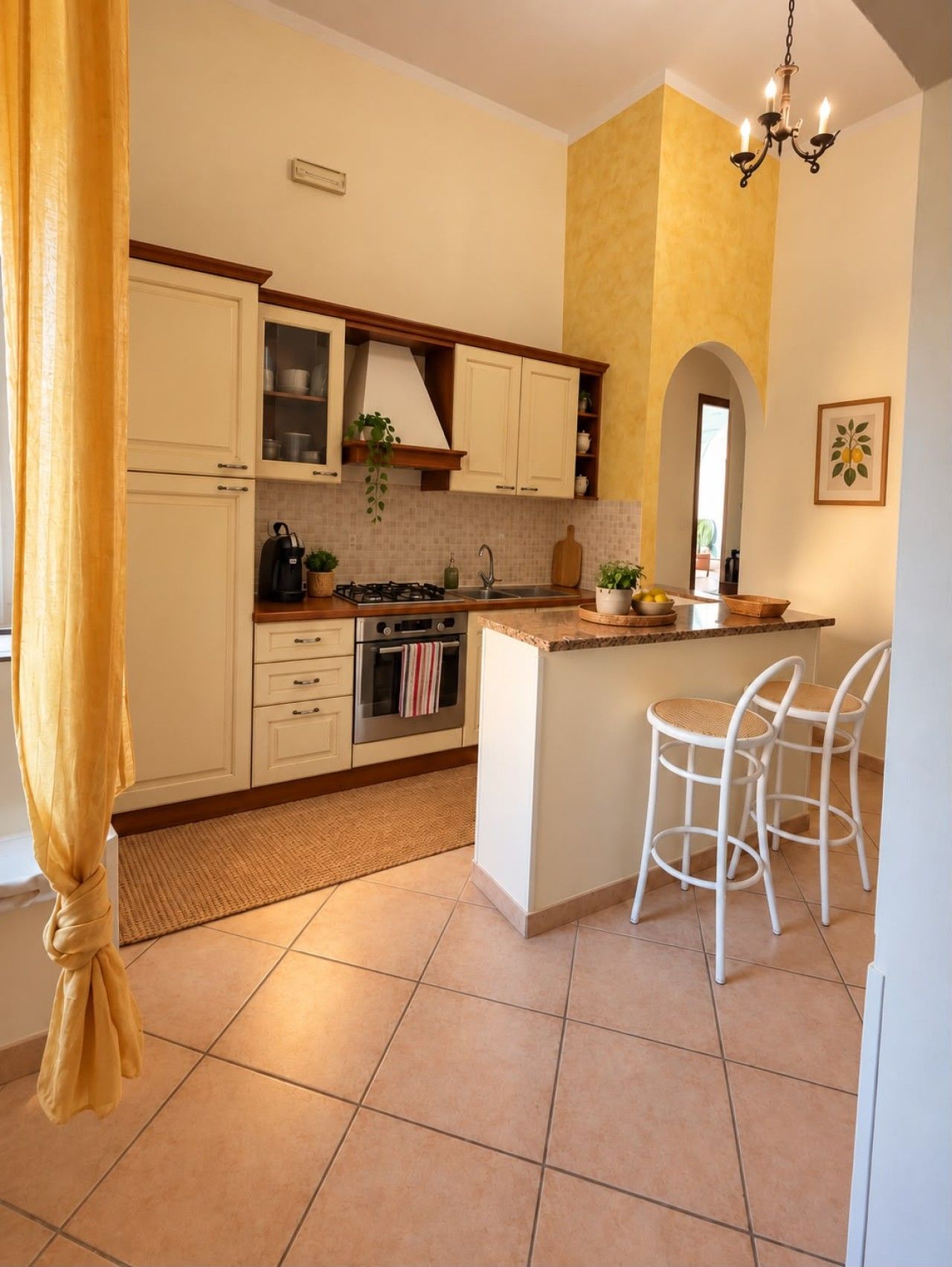 Una cucina con mobili bianchi, un fornello a gas, un lavello e una piccola isola con sgabelli da bar.
