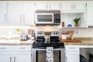 A kitchen with white cabinets, a microwave, a stove, a toaster, and a coffee maker. - Cozy 3BR Home with Mtn Views & Pool, Near Trails (Tucson)