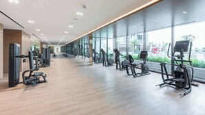 A modern gym with cardio machines, free weights, and a mirrored wall. - StayShort - Sophisticated JVC Apartment Sleeps 4 with Balcony (JVC)