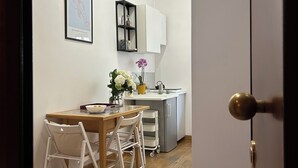 Ett modernt kök med vita skåp, en liten köksö och en matplats med ett träbord och vita stolar.
