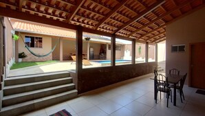 A covered outdoor area with a pool, steps leading to a building, and a dining table with chairs. - Vacation home in Pirenópolis (Pirenópolis)
