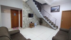 A living room with a staircase, a TV mounted on the wall, and two sofas. - Vacation home in Pirenópolis (Pirenópolis)