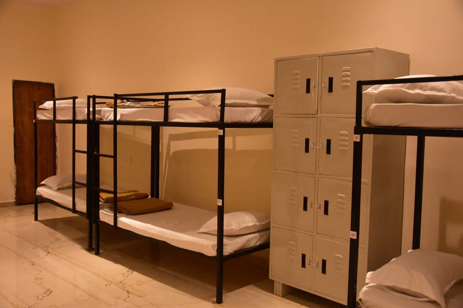A dormitory room with bunk beds and a set of lockers.
