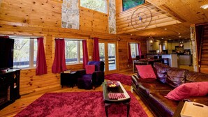 Interior de una cabaña de madera con sala de estar, comedor y cocina.