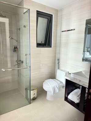 A modern bathroom with a glass-enclosed shower, a toilet, a sink, and a mirror. - Novelty Hotel (Ho Chi Minh City)