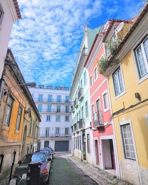 Una estrecha calle empedrada bordeada por edificios coloridos con balcones y un cielo azul despejado.