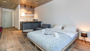 A compact hotel room with a bed, bedside table, and a small seating area. - New Gudauri Cozy Studio By Wehost (Gudauri)