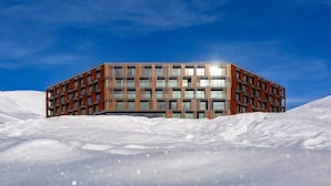 A modern building with a rectangular shape, multiple floors, and a flat roof, surrounded by snow. - Studio near Gondola in New Gudauri by Wehost (Gudauri)