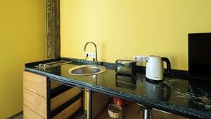 Una cocina compacta equipada con lavamanos, tostadora, hervidor y microondas.