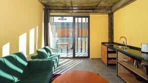 Una sala de estar moderna con un sofá verde, una mesa de centro y un ventanal corredero que da a un balcón.