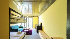 Una habitación pequeña con literas, un sofá, un escritorio y una ventana.