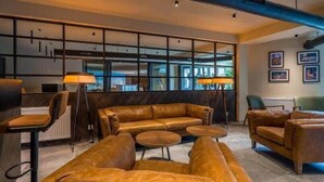 Ein stilvoller Lounge-Bereich mit Ledersofas, einem Couchtisch und einem Schreibtisch mit Lampe.