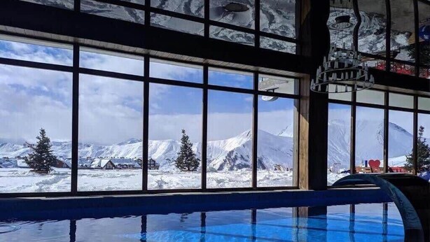 Ein Hallenbad mit Blick auf verschneite Berge durch große Fenster.