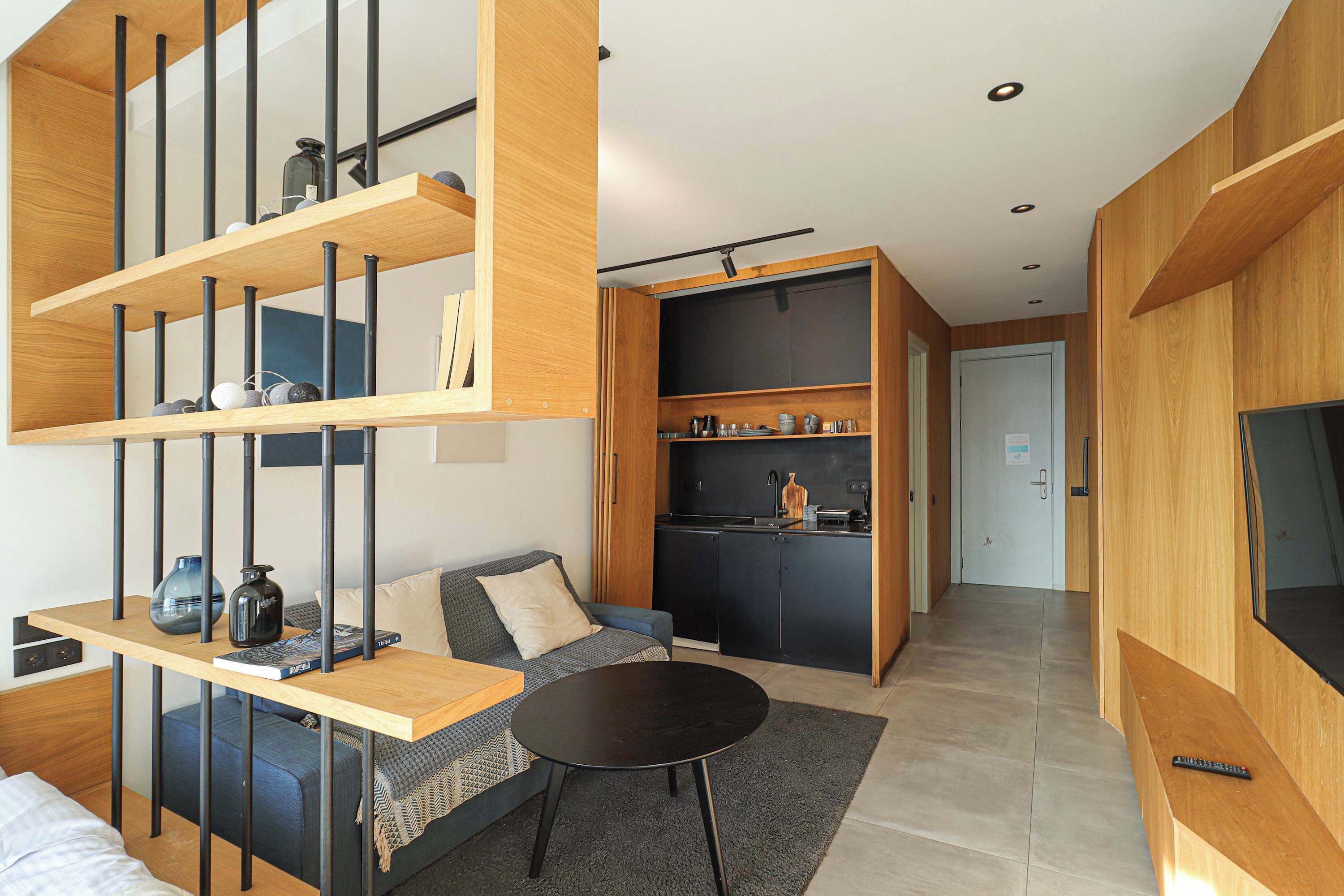 Un espacio de estar moderno con un sofá, una mesa de centro y una zona de cocina con armarios y una encimera.