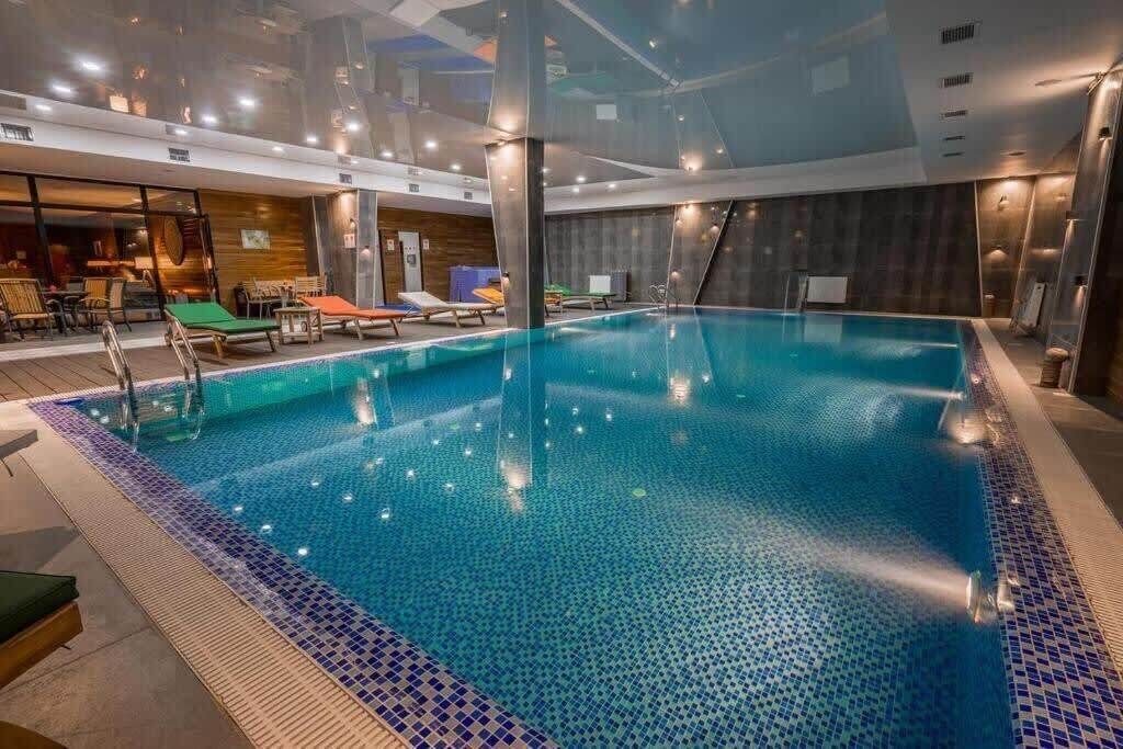 Una piscina interior amb aigua blava cristal·lina, envoltada de gandules i una paret de fusta.