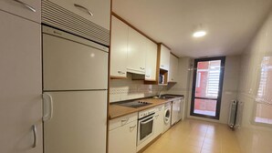 A compact kitchen with a refrigerator, oven, sink, and washing machine. - Apartamentos el Pilar Suites 3000 (Zaragoza)