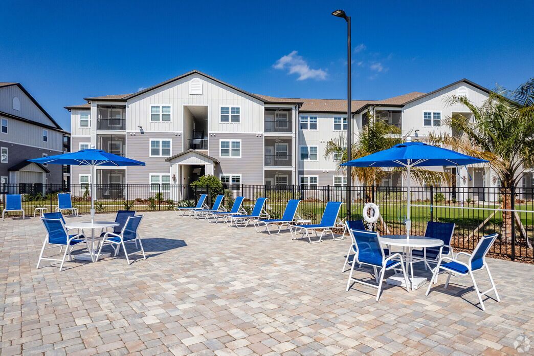 A courtyard with outdoor seating, a building entrance, and a fence.