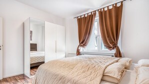 Un dormitorio con una cama, un espejo grande y una ventana con cortinas.
