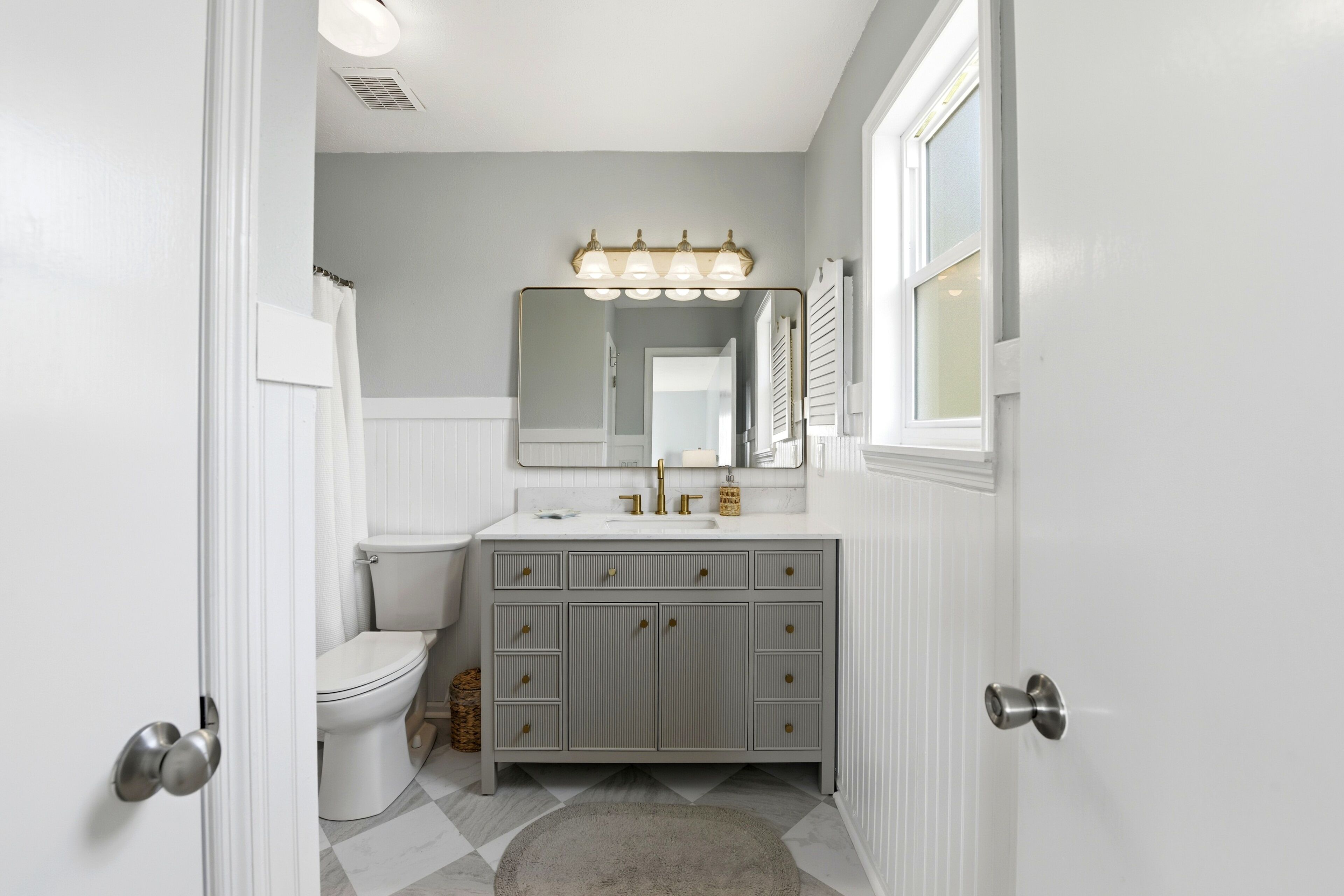 Une salle de bain avec un meuble-lavabo blanc, un miroir et des toilettes.