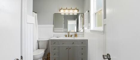 Une salle de bain avec un meuble-lavabo blanc, un miroir et des toilettes.