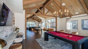 Une pièce spacieuse équipée d’une table de billard, d’un coin bar et offrant une vue sur l’extérieur.