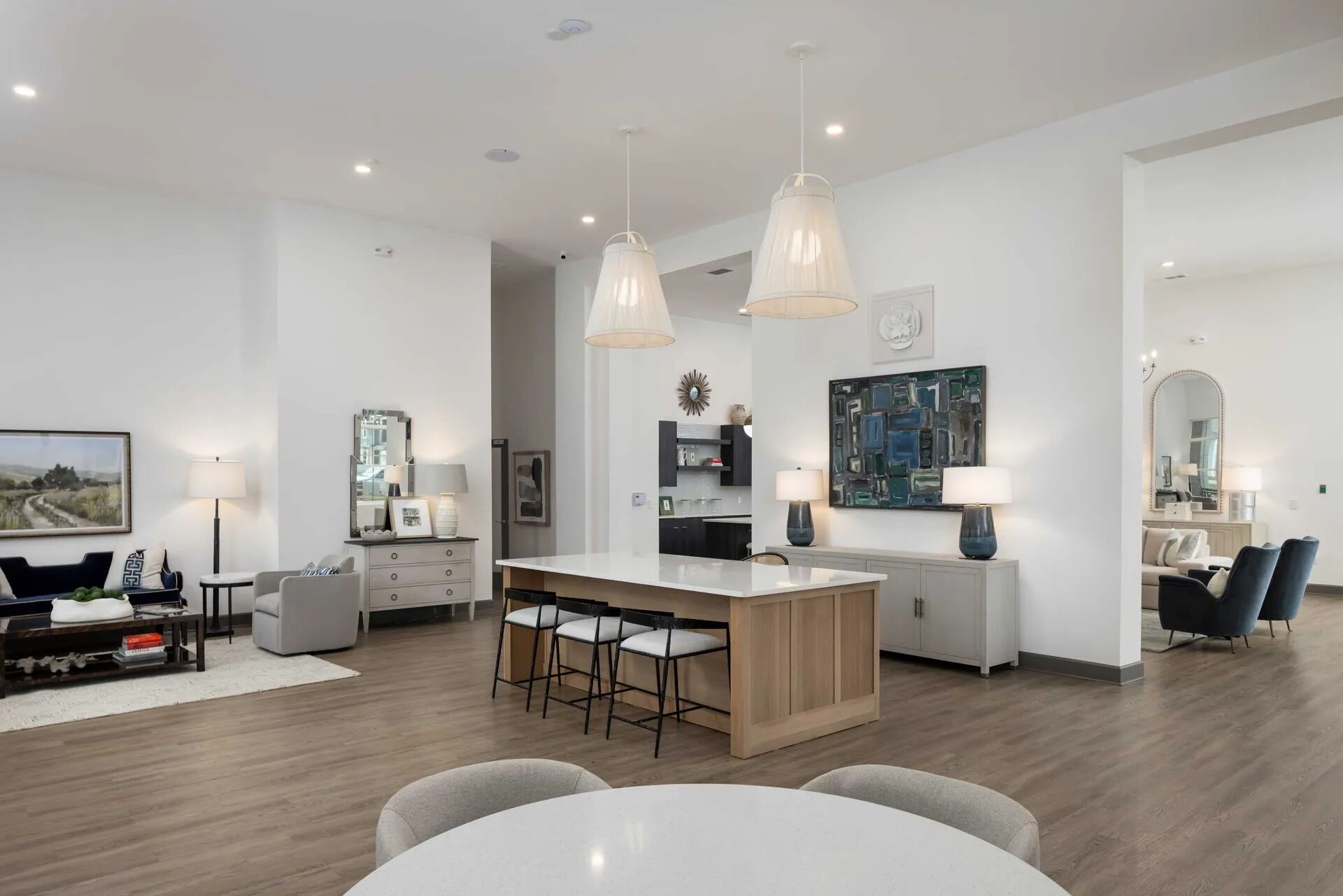 A modern kitchen with a central island, pendant lighting, and a dining area with a round table.