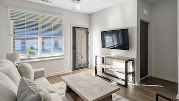 Una sala de estar moderna con sofá, mesa de centro, televisor y estanterías empotradas.