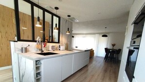 A modern kitchen with a large island, wooden flooring, and pendant lighting. - A stone's throw from the medieval town, pretty house ideal for families (Carcassonne)