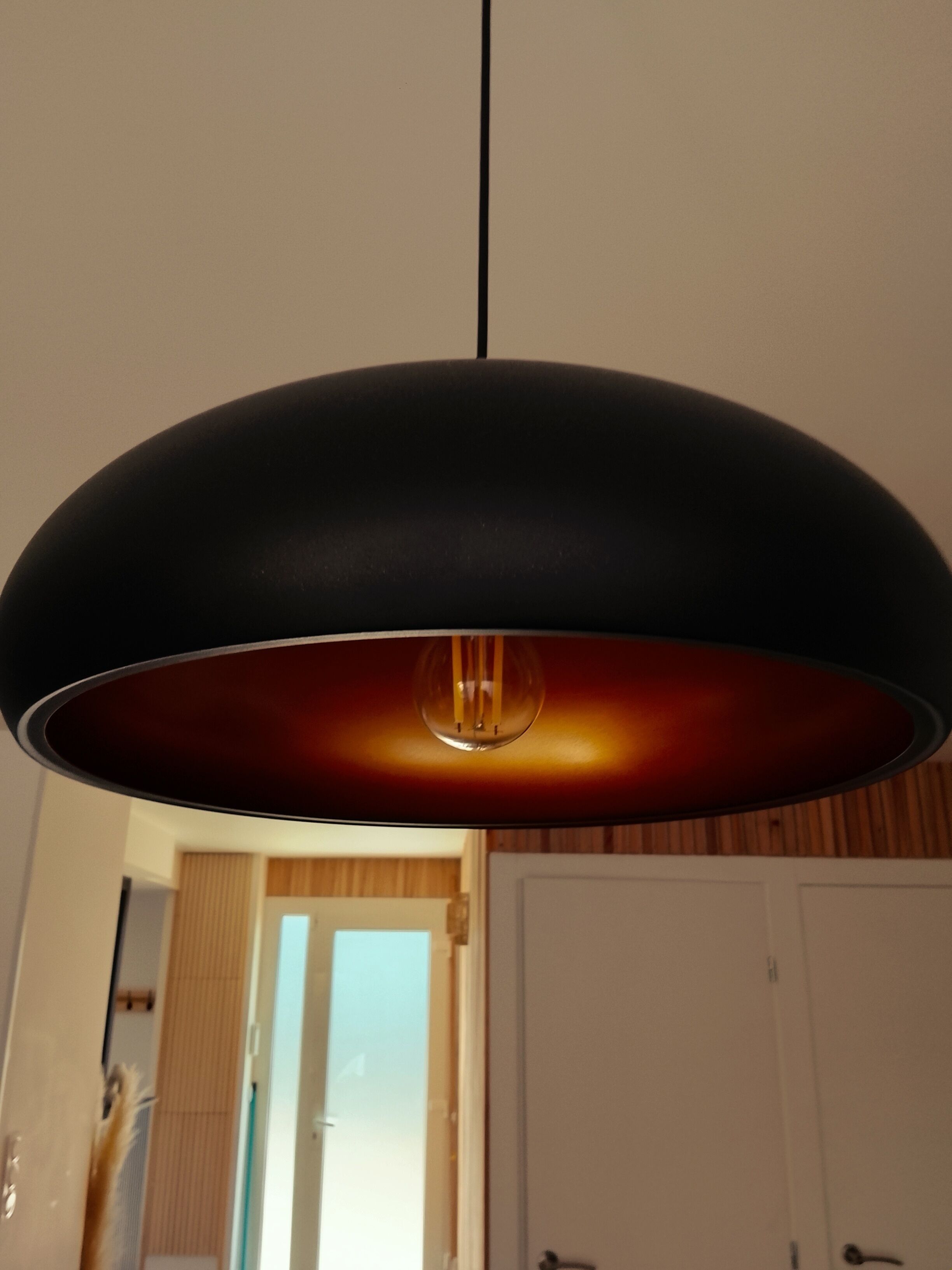 Una lámpara colgante en una habitación con paneles de madera y puertas blancas.