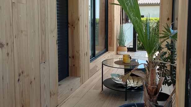 A modern interior with wooden walls, a glass door, and a small round table with a plant. - A stone's throw from the medieval town, pretty house ideal for families (Carcassonne)