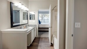 A narrow hallway with a bathroom featuring a sink, mirror, and window. - Landing Furnished Apartments near Barfield (Murfreesboro)
