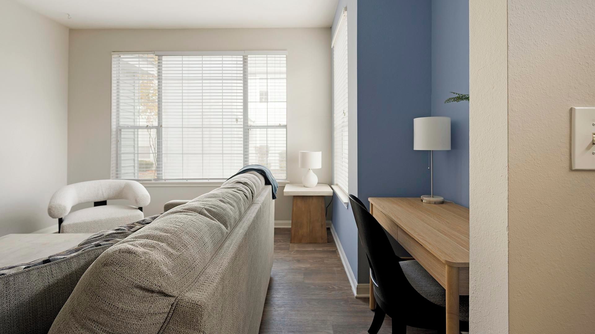 A modern living room with a sofa, a wooden desk, and a chair.
