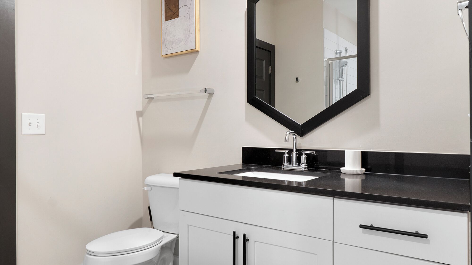A modern bathroom with a black countertop, white sink, and a large mirror.