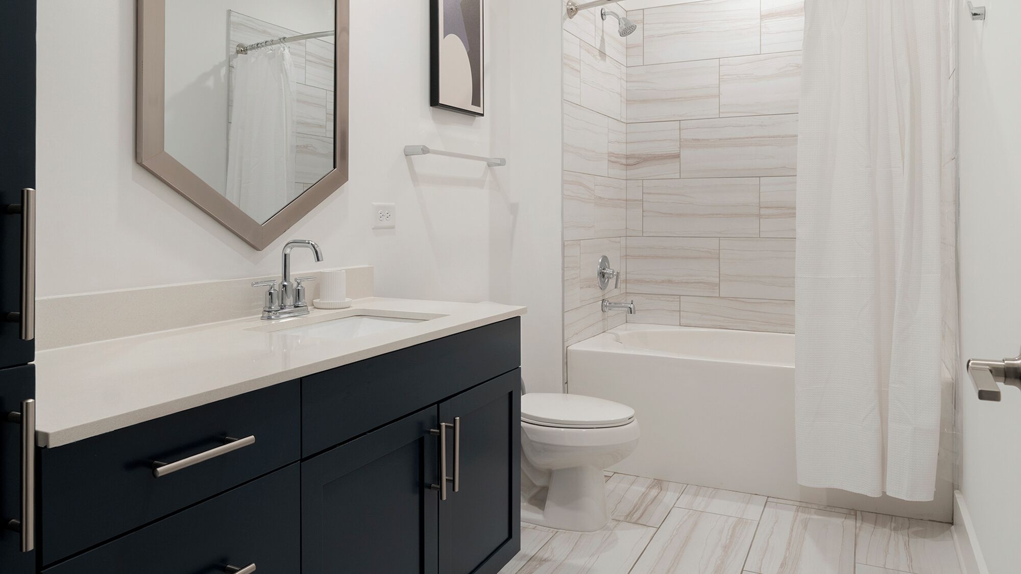 A modern bathroom with a double sink vanity, a toilet, and a bathtub.