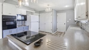 A modern kitchen with white cabinets, a black stove, a white refrigerator, and a granite countertop. - Large family friendly country home (Monett)