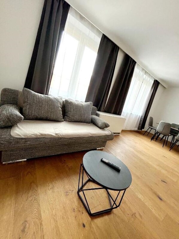 A modern living room with a sofa, a round coffee table, and a dining area with chairs.