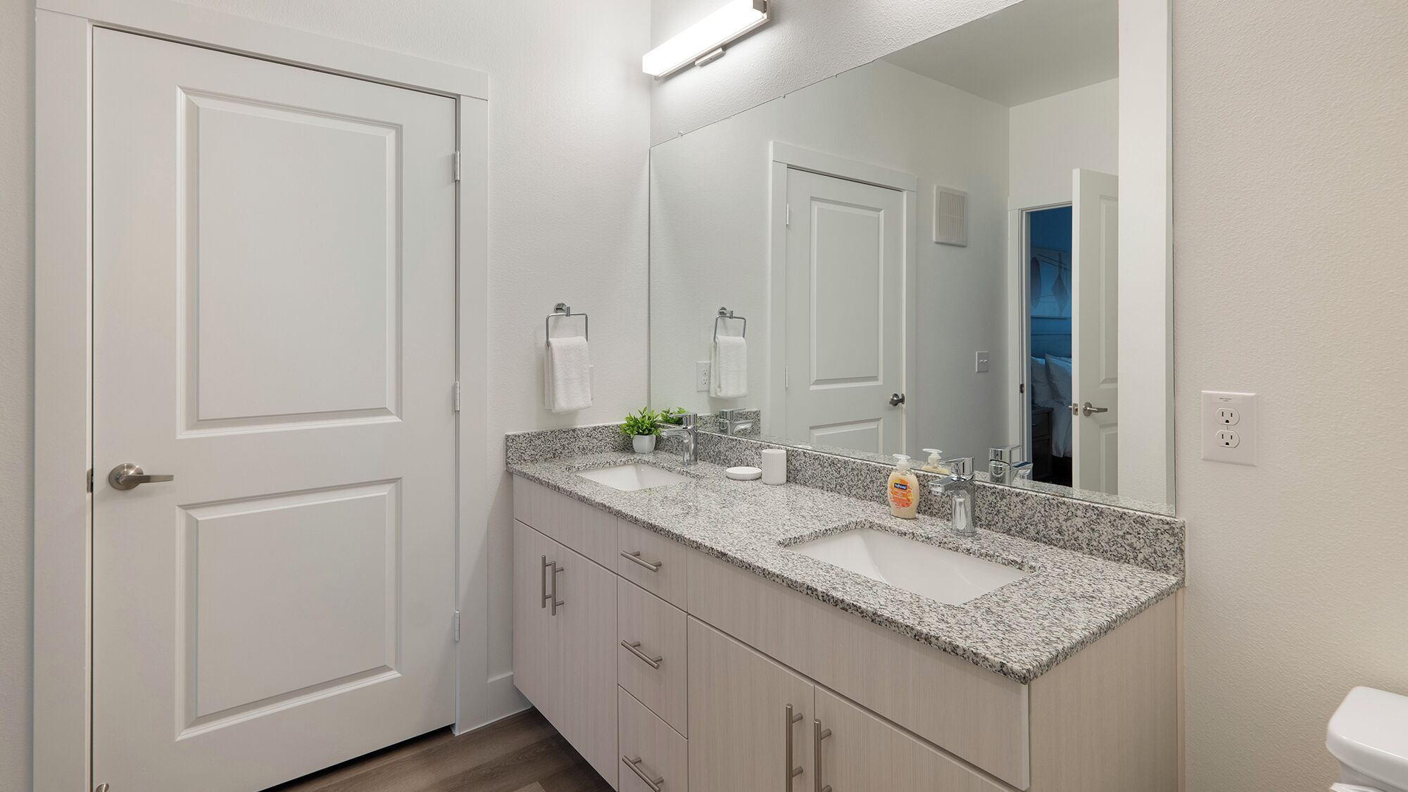 A modern bathroom with a granite countertop, a large mirror, and a white toilet.