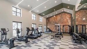 A spacious gym with treadmills, elliptical machines, and a piano. - Landing Apartments - Leander (Leander)