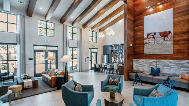 A spacious lobby with modern furniture, large windows, and a wooden accent wall. - Landing Apartments - Leander (Leander)