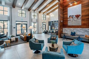 A spacious lobby with modern furniture, large windows, and a wooden accent wall. - Landing Apartments - Leander (Leander)