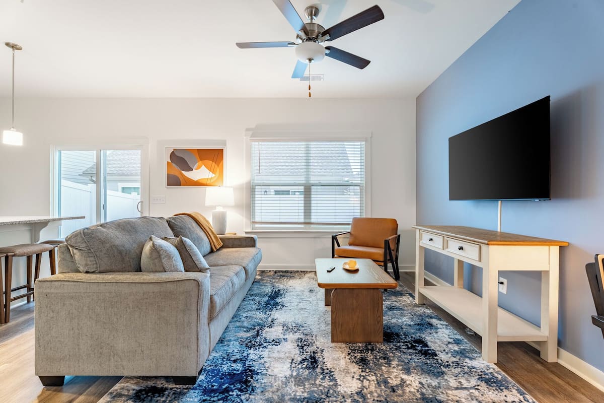 A modern living room with a sofa, coffee table, and a TV mounted on the wall.